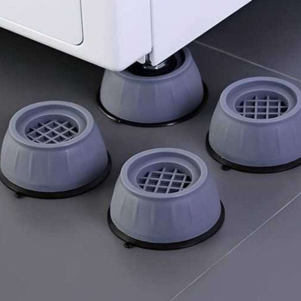 Four gray rubber furniture glides on a floor with a piece of furniture partially visible.